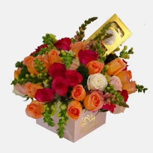 Arreglo floral en caja rosa con rosas fucsia, naranjas y chocolates Ferrero Rocher para entrega a domicilio en Guayaquil.