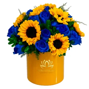 Box dorada con vibrantes girasoles y rosas azules para entrega a domicilio en Guayaquil con MilliersD'fleurs.